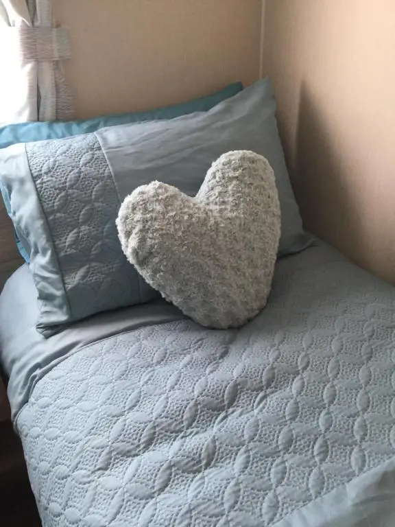 a heart pillow sitting on top of a bed at Poppy Lodge in Boat of Garten