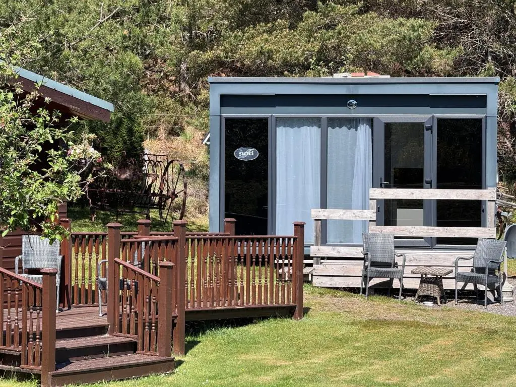 a house with a deck and chairs in the yard at The Garden Room Tiny House Bed and Breakfast Stay in Glenmoriston