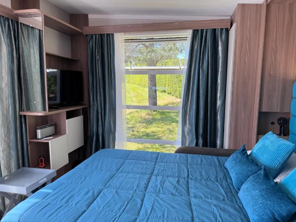 a bedroom with a blue bed and a large window at The Garden Room Tiny House Bed and Breakfast Stay in Glenmoriston