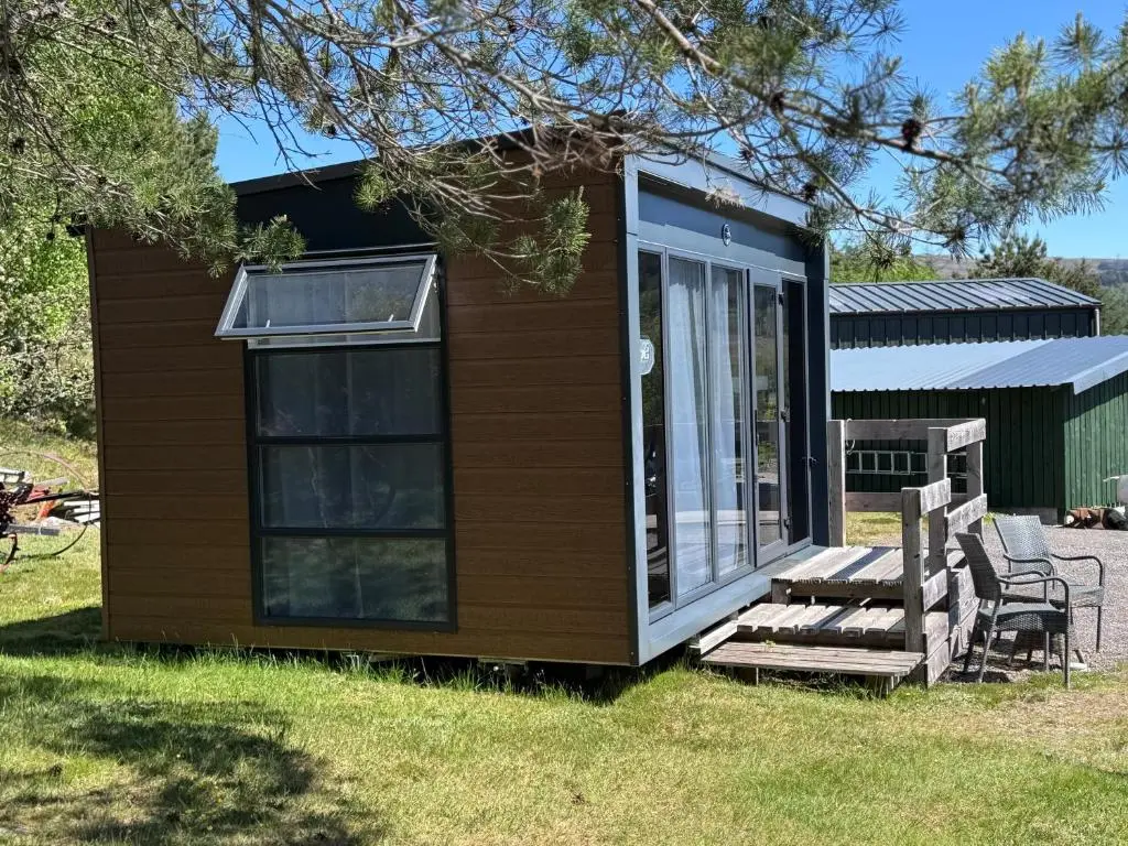 a tiny house with a porch and two chairs at The Garden Room Tiny House Bed and Breakfast Stay in Glenmoriston