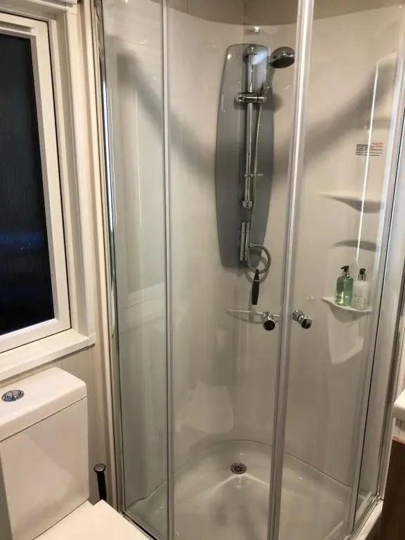 a shower with a glass door in a bathroom at The Garden Room Tiny House Bed and Breakfast Stay in Glenmoriston