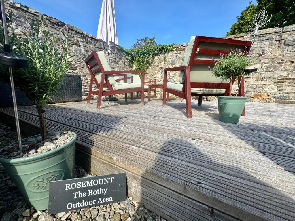 a couple of chairs and a sign on a wooden deck at Rosemount Bothy - Highland Cottage in Garve