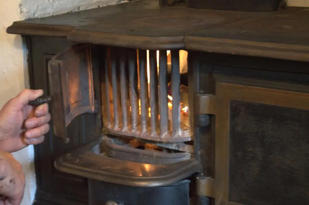 a person is putting something in a wood stove at Rosemount Bothy - Highland Cottage in Garve