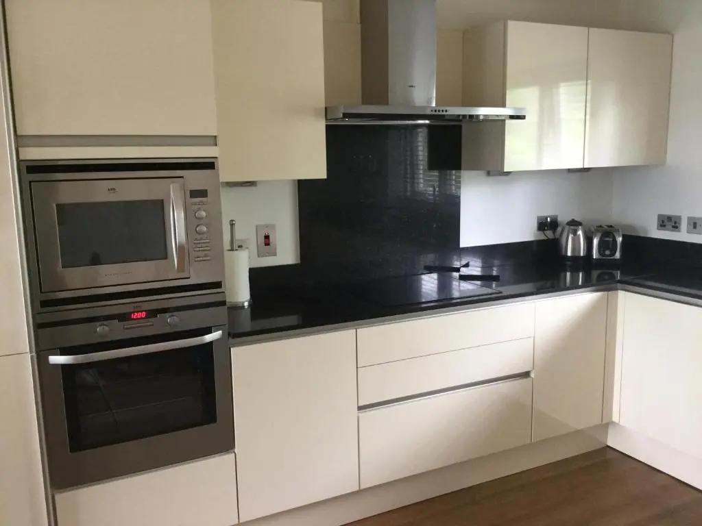 a kitchen with white cabinets and a microwave at Castlefield Apartment Free Parking in Inverness