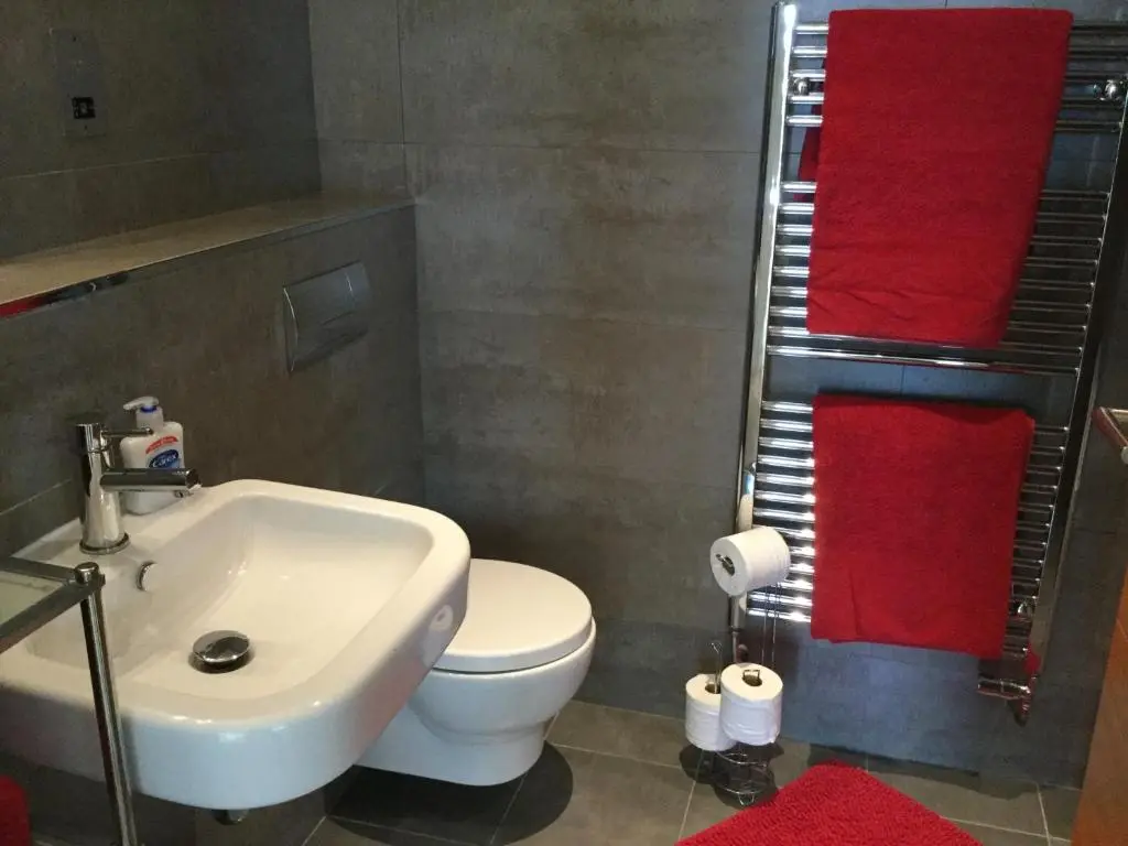 a bathroom with a toilet and a sink and red towels at Castlefield Apartment Free Parking in Inverness