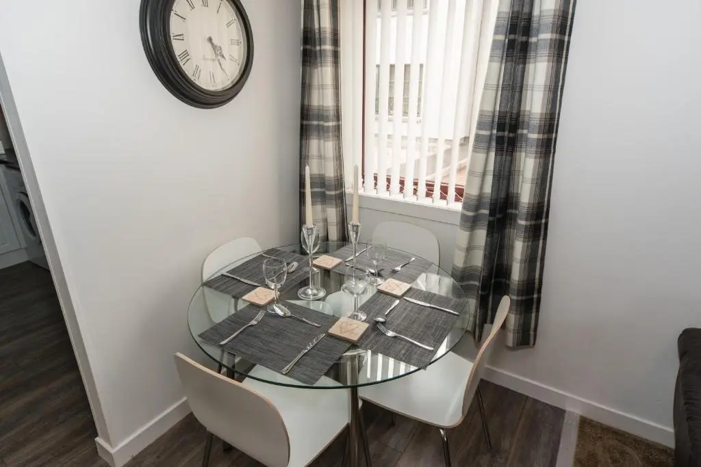 a dining room table with chairs and a clock on the wall at Silver Key Apartments in Inverness