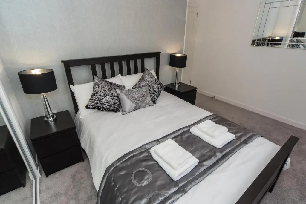 a bedroom with a large white bed with two lamps at Silver Key Apartments in Inverness