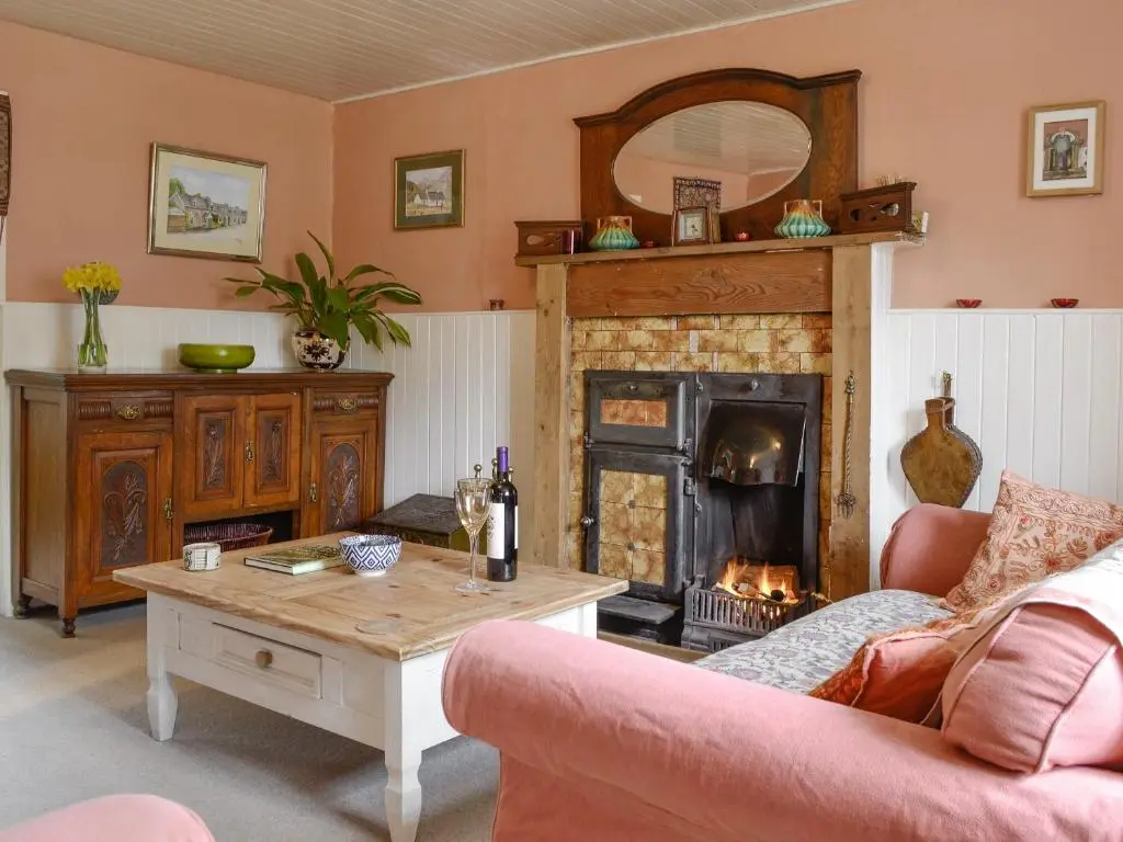 a living room with a table and a fireplace at Larch Cottage in Balnald