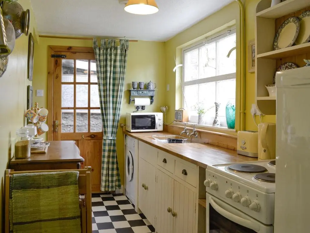 a kitchen with yellow walls and a sink and a refrigerator at Larch Cottage in Balnald