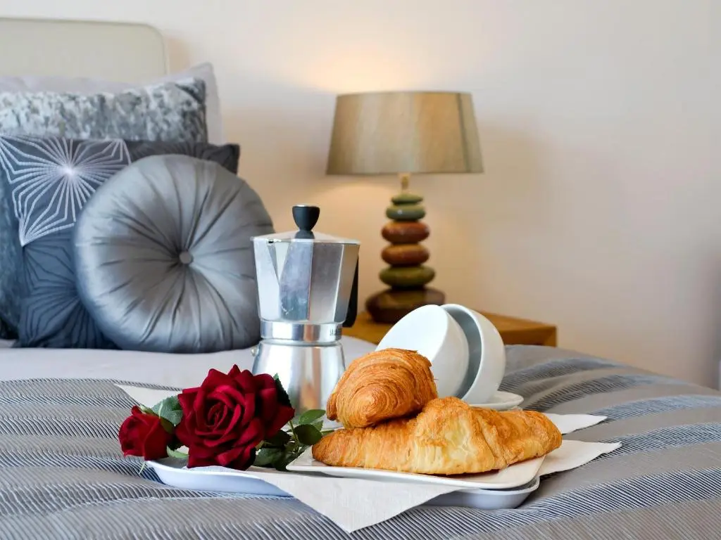 a tray with a plate of croissants and roses on a bed at Seascape in Whitehills