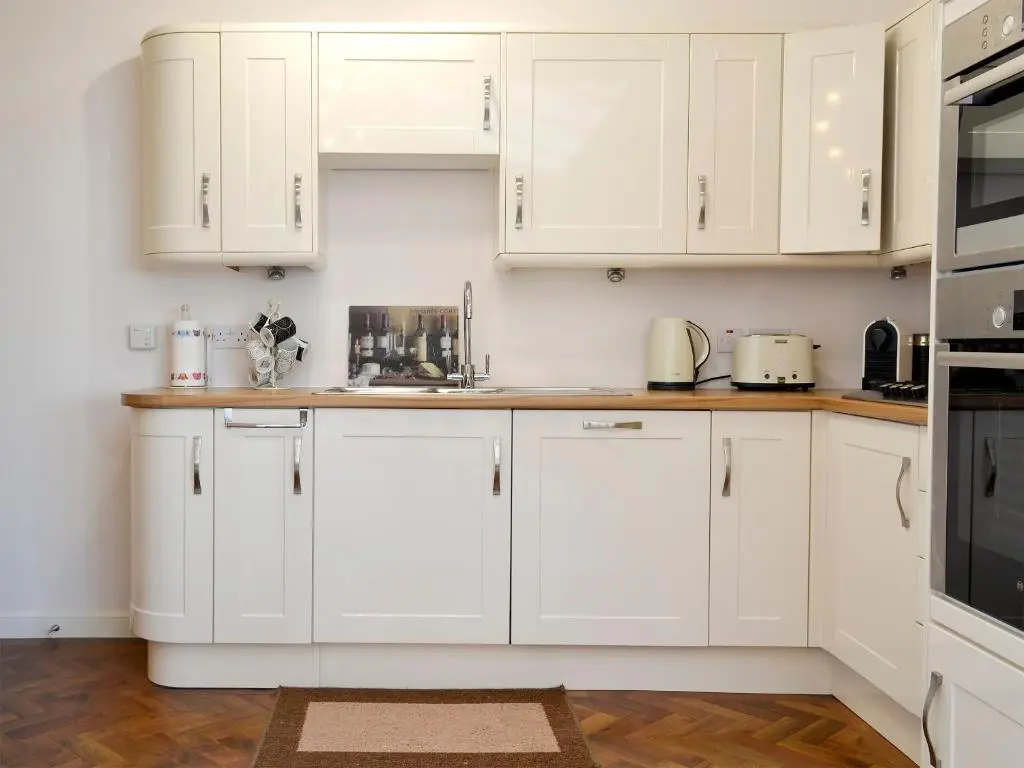 a white kitchen with white cabinets and appliances at Seascape in Whitehills