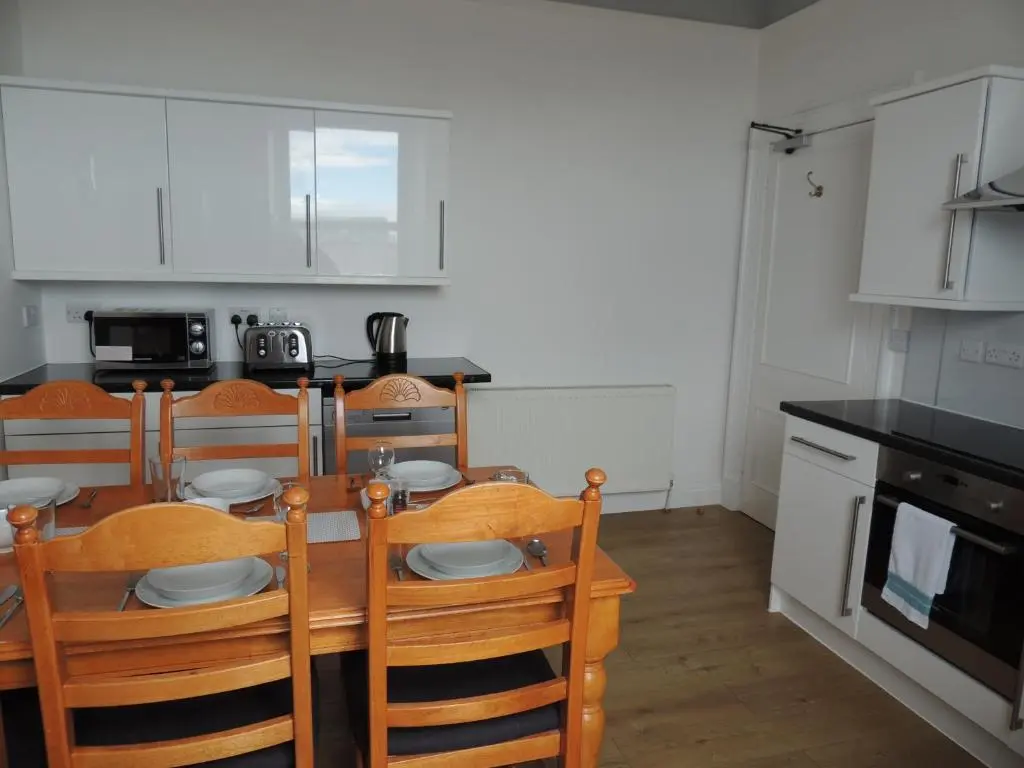 a kitchen with a wooden table and chairs and a dining room at 5A Union Road in Macduff
