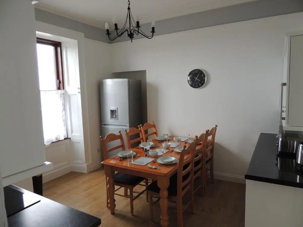 a dining room table with chairs and a refrigerator at 5A Union Road in Macduff