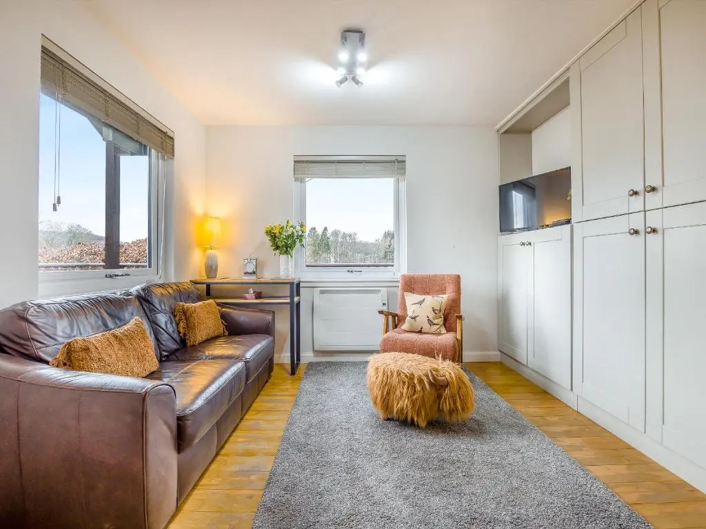 a living room with a brown couch and a chair at Boreland Farm Cabin - Uk5855 in Kirkmichael