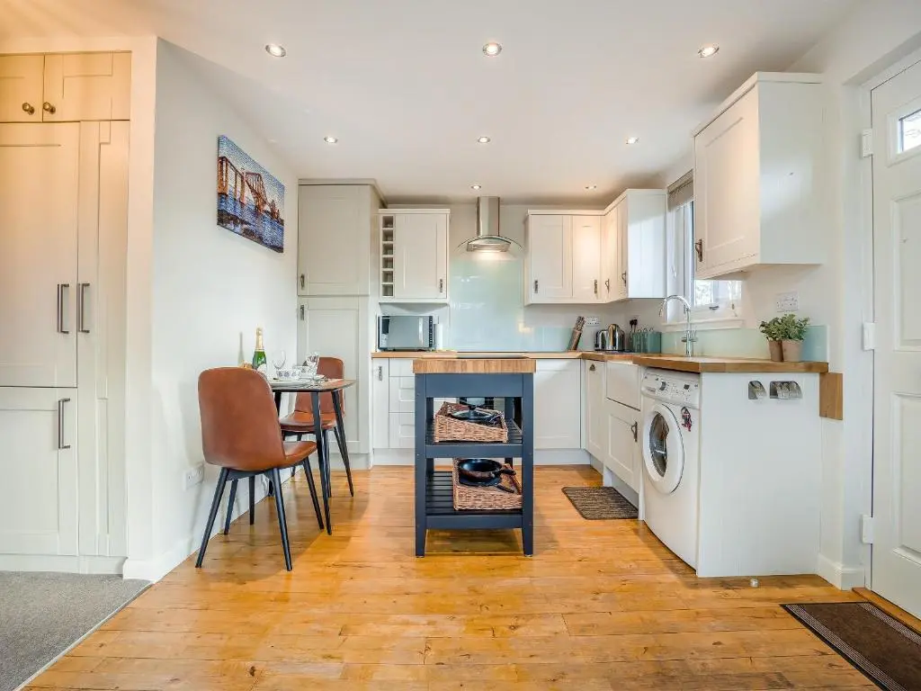 a kitchen with white cabinets and a table at Boreland Farm Cabin - Uk5855 in Kirkmichael