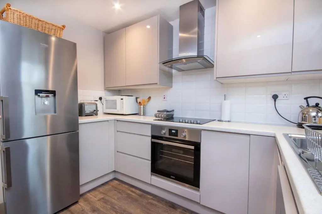a kitchen with white cabinets and a stainless steel refrigerator at Aviemore Highlands No82 in Aviemore