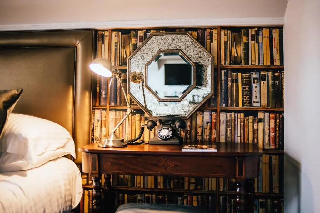 a mirror on a table next to a book shelf at Banchory Lodge Hotel in Banchory