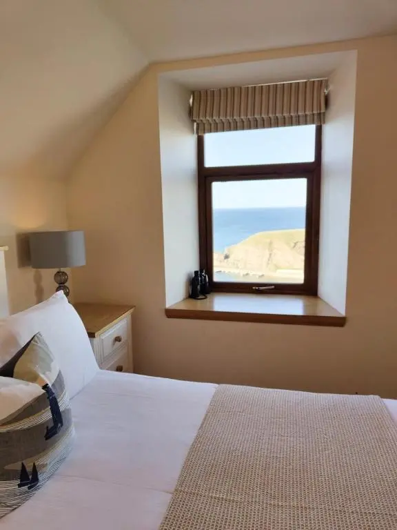 a bedroom with a bed and a window with the ocean at Portknockie 17 Harbour Place in Portknockie