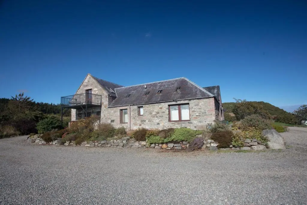 a stone house on a hill with a gravel driveway at Dolphin View Hillockhead in Rosemarkie