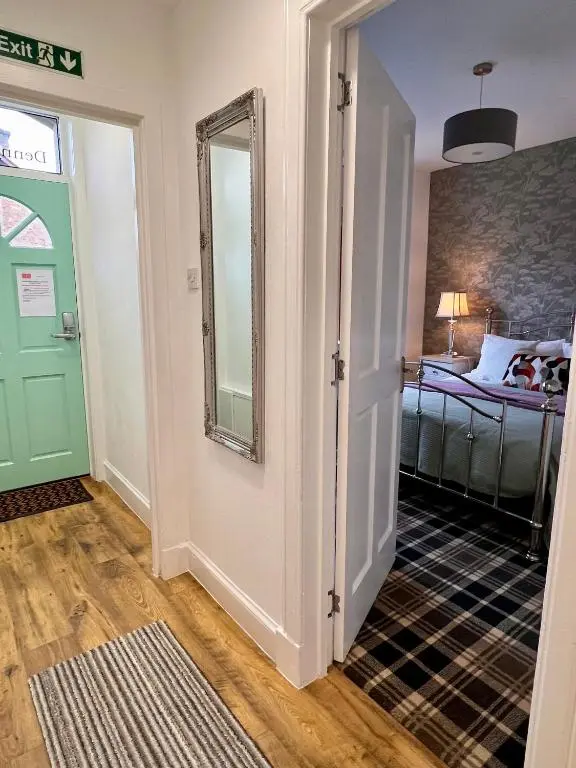 a hallway with a door and a mirror and a bedroom at The Stags Head Apartment in Inverness