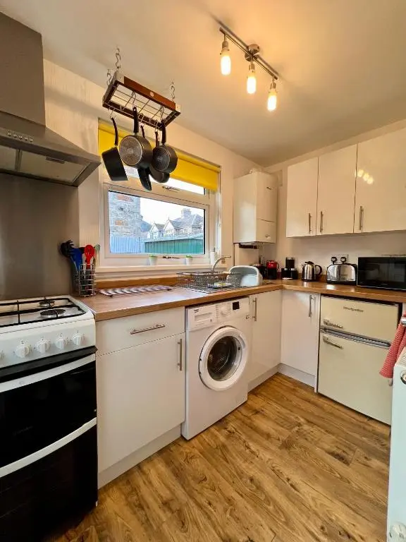 a kitchen with white cabinets and a washer and dryer at The Stags Head Apartment in Inverness
