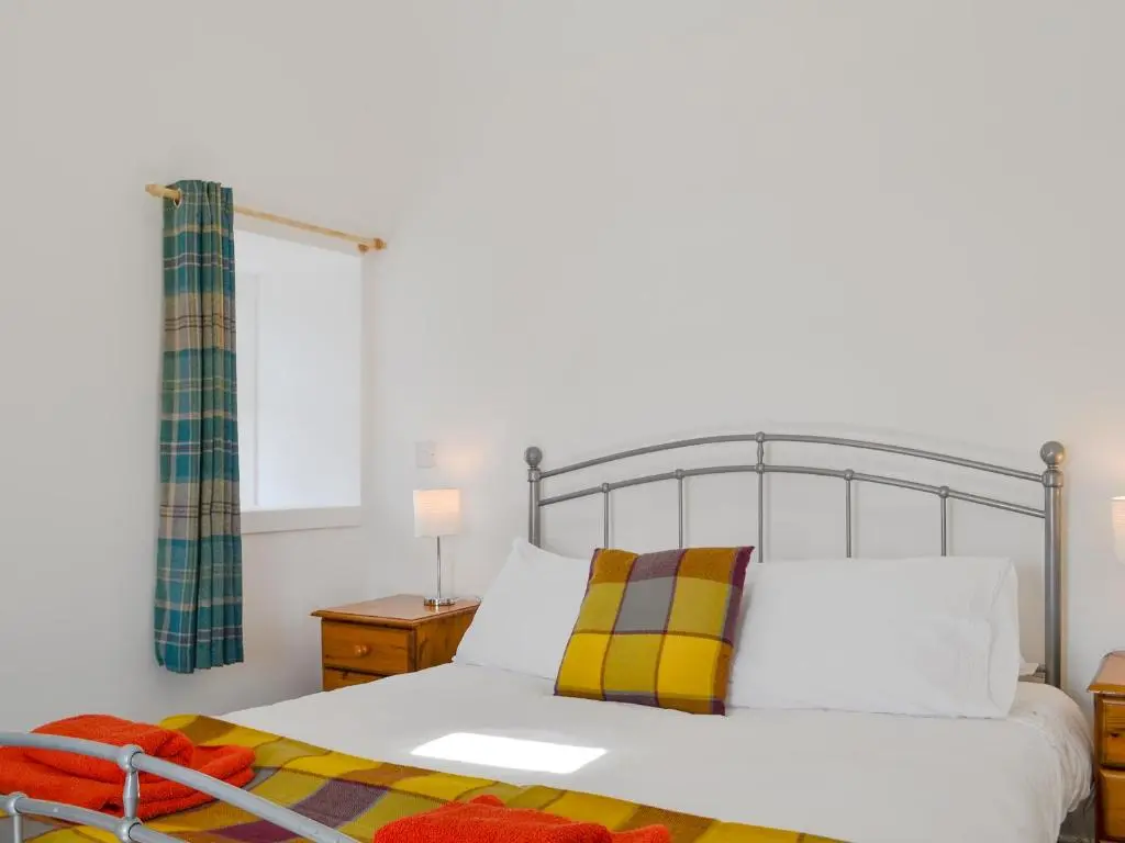 a bedroom with a large white bed and a window at Wester Laggan Cottage in Skye of Curr