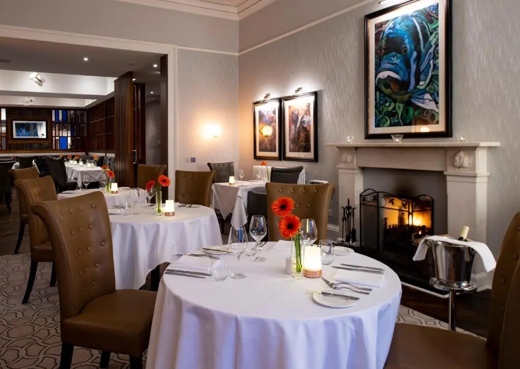 a restaurant with white tables and chairs and a fireplace at Ness Walk in Inverness