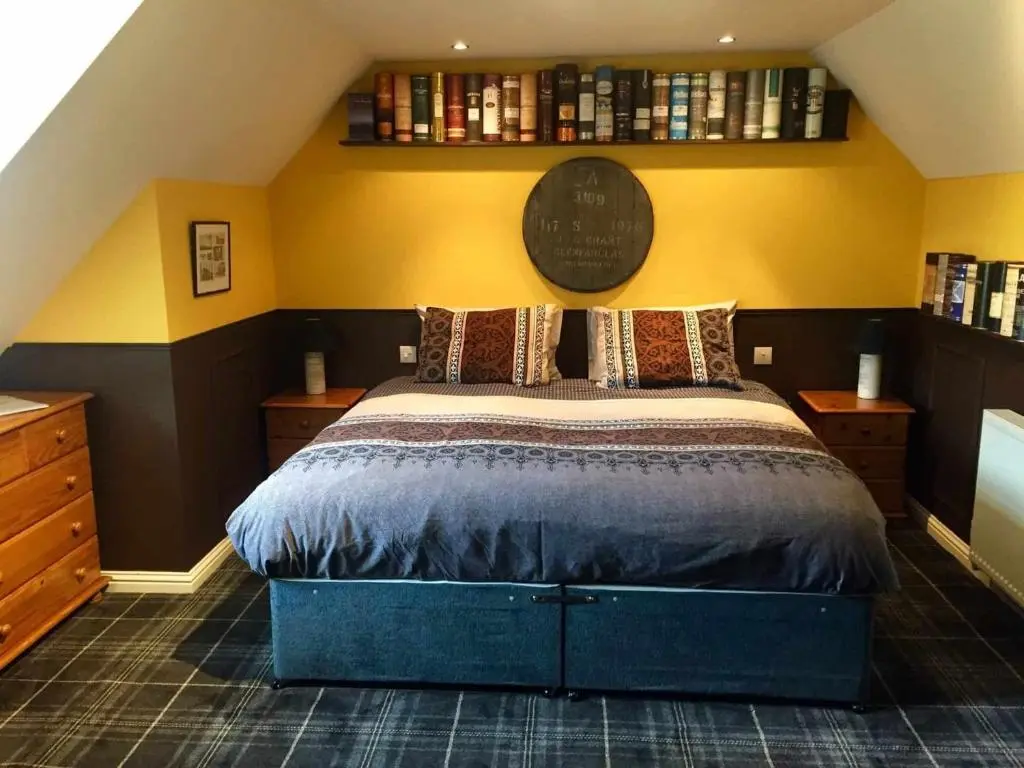 a bedroom with a large bed and a yellow wall at The Gables Whisky B&B in Dufftown