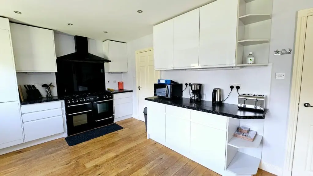 a kitchen with white cabinets and black counter tops at 26 Woodgrove Drive in Inverness