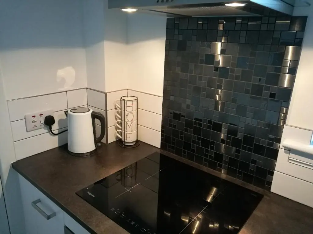 a small kitchen with black tiles on the wall at The Hedgehogs in Inverness