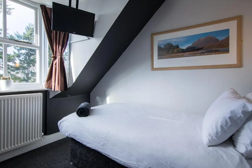 a bedroom with a white bed and a window at Bazpackers in Inverness