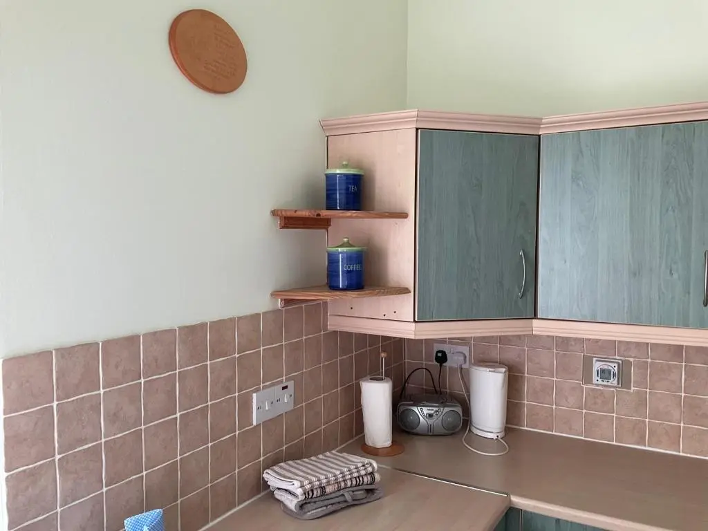a kitchen with pink tiles and green cabinets at Courtyard Cottage Free Parking in Inverness