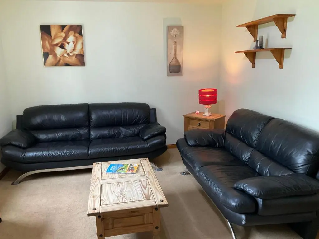 a living room with a black leather couch and a coffee table at Two Bedroom Glen View Free Parking in Inverness
