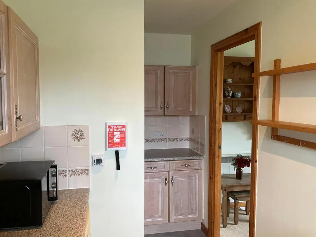 a kitchen with wooden cabinets and a room with a table at Two Bedroom Glen View Free Parking in Inverness