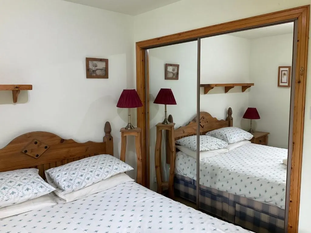 a bedroom with two beds and a mirror at Two Bedroom Glen View Free Parking in Inverness