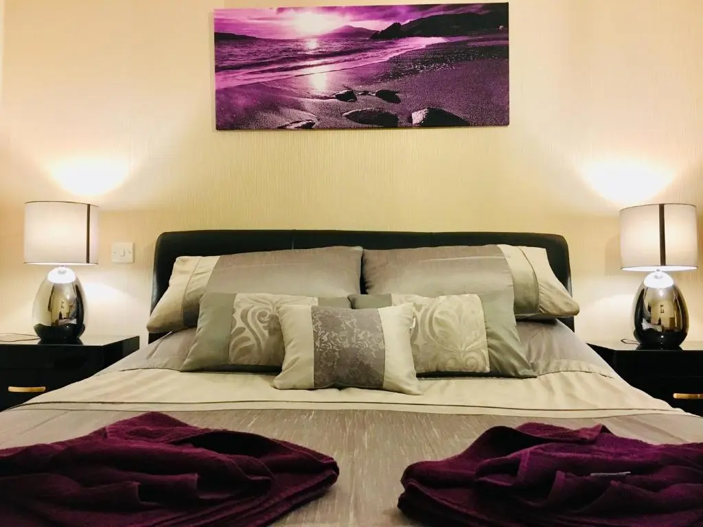 a bedroom with a large bed with two lamps at Azim and Suzi\u2019s city centre apartment Inverness in Inverness