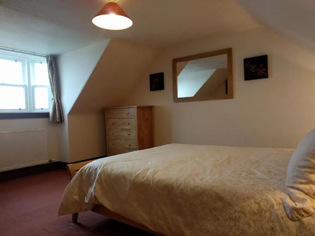 a bedroom with a bed and a mirror on the wall at Sandend Cottage in Banff
