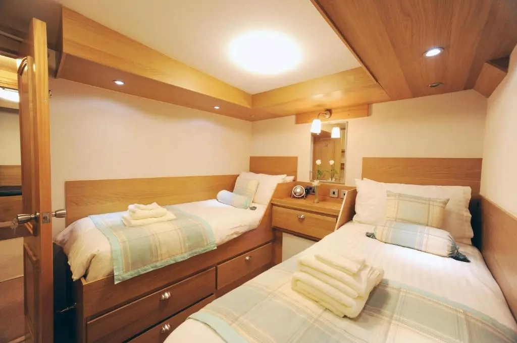 two beds in a small room with wooden cabinets at The Boat and Breakfast in Inverness