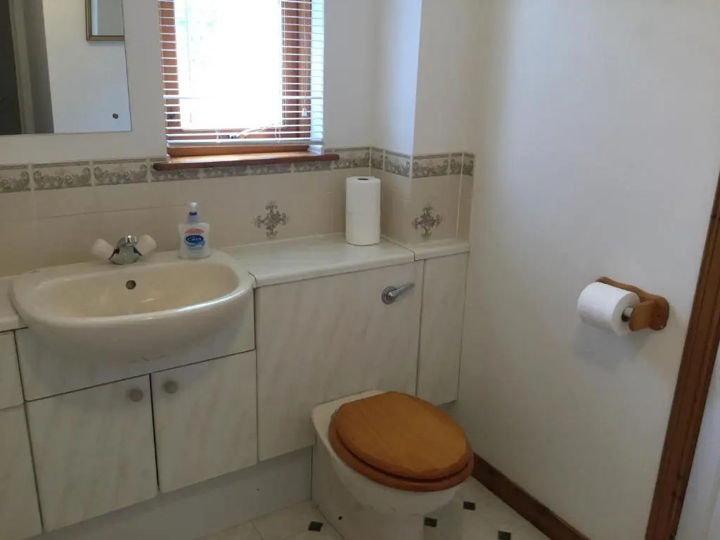 a bathroom with a toilet and a sink and a mirror at Two-Bedroom Apartment - Golf View Free Parking in Inverness