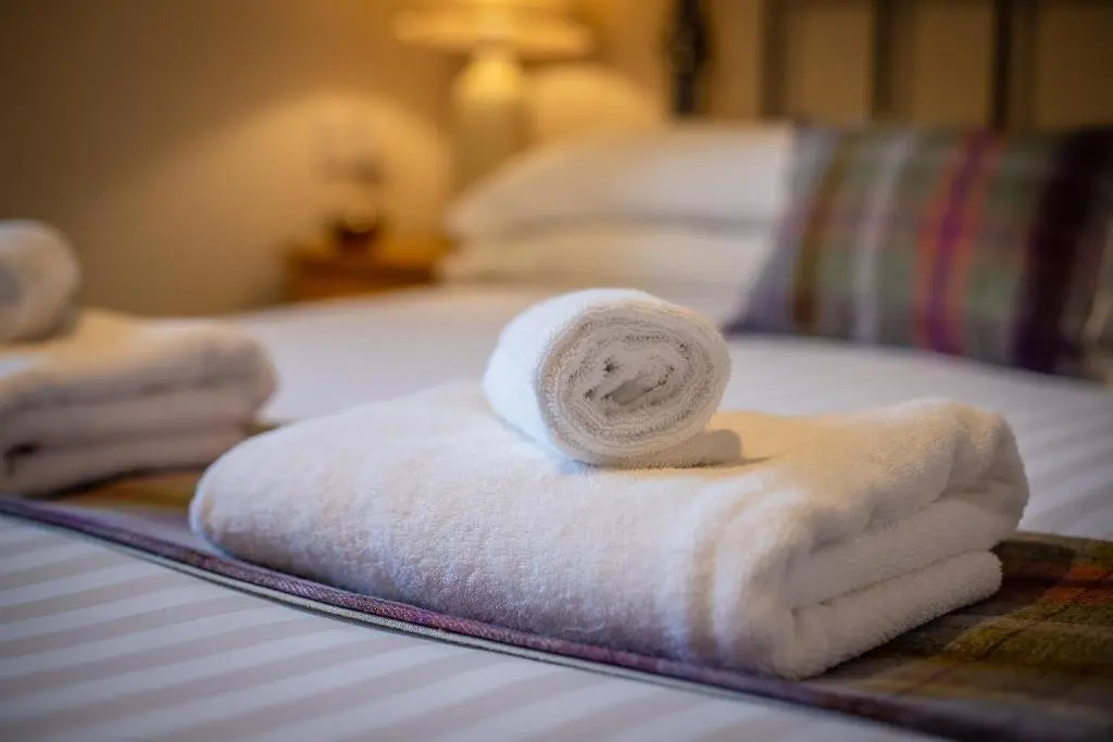 a pile of towels sitting on top of a bed at Douglas House Apartments in Nairn