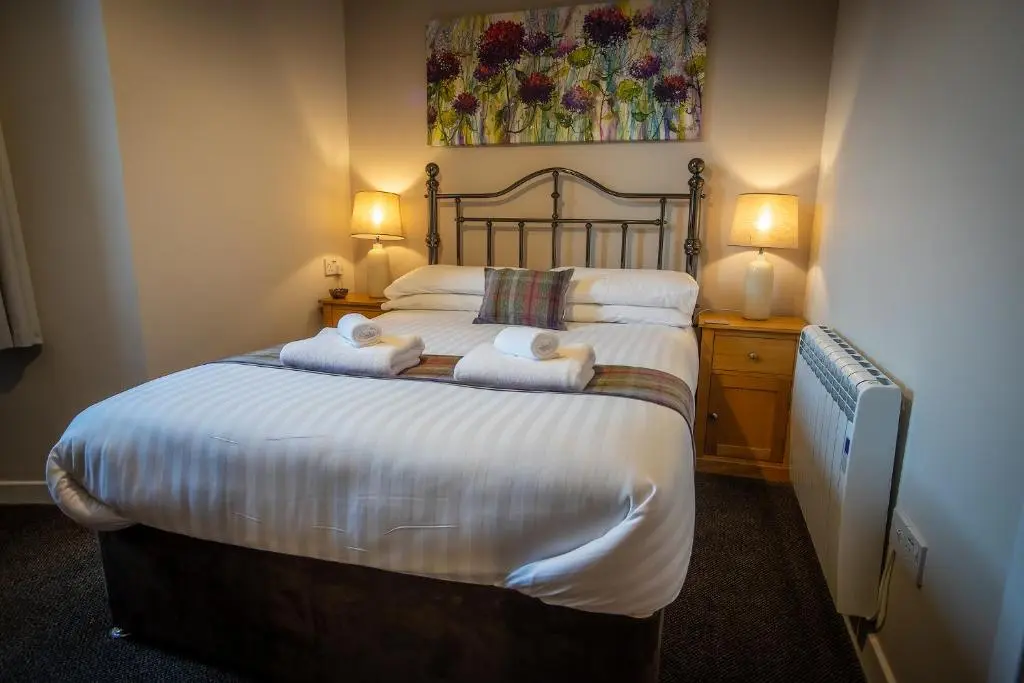 a bedroom with a large bed with towels on it at Douglas House Apartments in Nairn