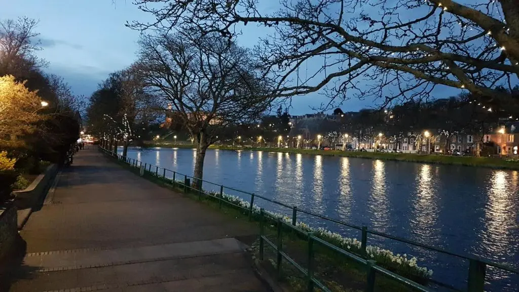 a river at night with a sidewalk next to it at 37 Farraline Court, City Centre apartment in Inverness