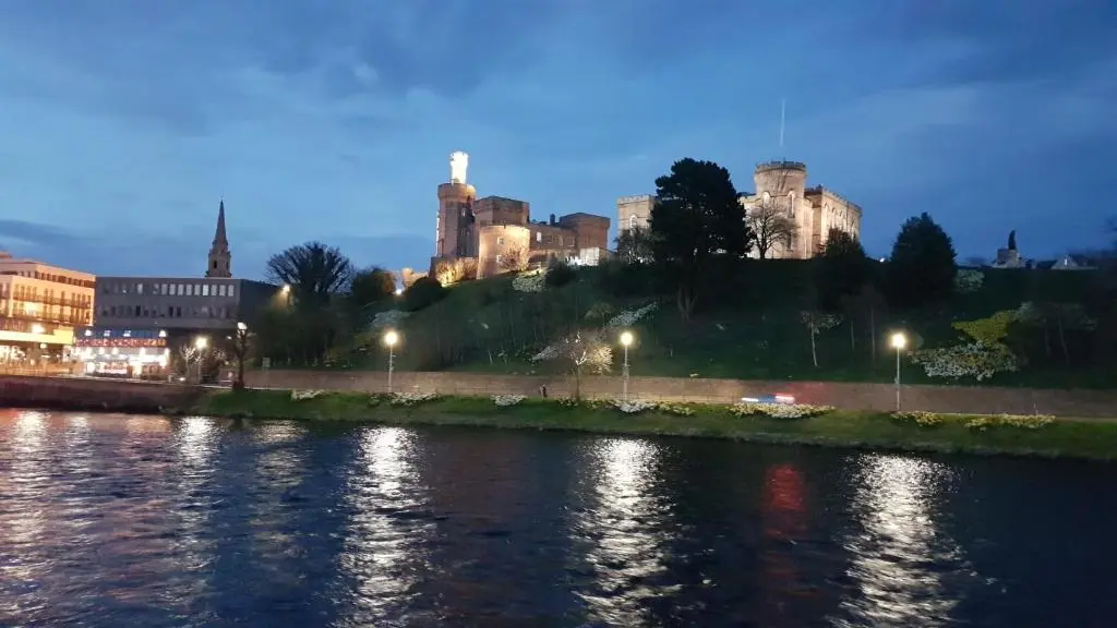a view of a city from a river at night at 37 Farraline Court, City Centre apartment in Inverness