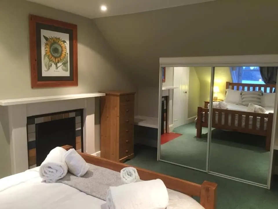 a bedroom with a bed with a fireplace and a mirror at The Cottage Aberlour in Aberlour