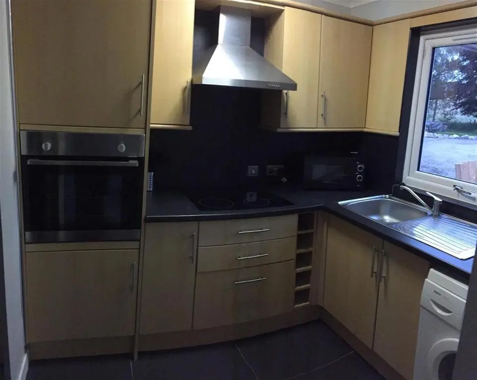 a kitchen with wooden cabinets and a sink and a window at The Cottage Aberlour in Aberlour