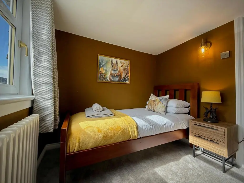 a bedroom with a bed with a yellow bedspread at Wells Street Cottages No 26 By The River Ness in Inverness