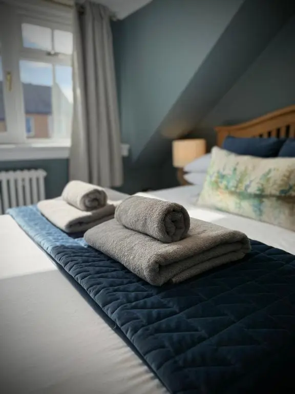 two towels on a bed in a hotel room at Wells Street Cottages No 26 By The River Ness in Inverness