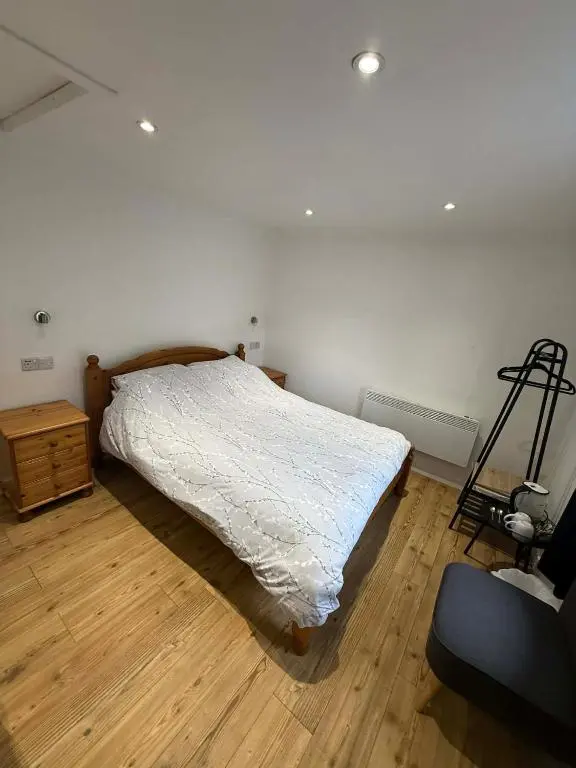 a bedroom with a white bed and a wooden floor at The Carisbrooke in Forres