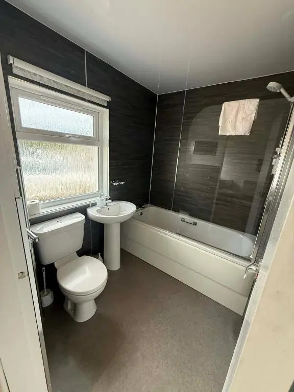 a bathroom with a toilet and a tub and a sink at The Carisbrooke in Forres