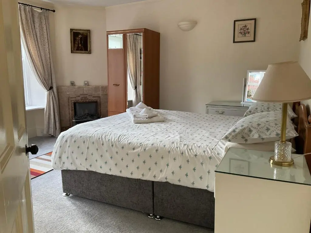 a bedroom with a bed and a table with a lamp at Three-Bedroom Old Cottage Free Parking in Inverness